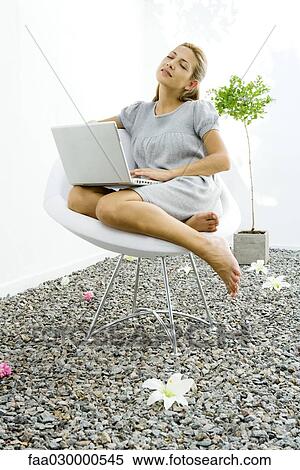 Woman sitting in chair in rock garden, holding laptop computer, eyes closed View Large Photo Image Stock Photography - Woman sitting in chair in rock garden, holding laptop computer, eyes closed. Fotosearch