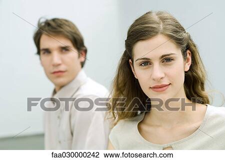 Woman smiling at camera, man behind, looking at woman View Large Photo Image Stock Image - Woman smiling at camera, man behind, looking at woman. Fotosearch
