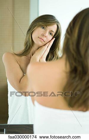 Woman standing in bath towel, looking at self in mirror View Large Photo Image Picture - Woman standing in bath towel, looking at self in mirror. Fotosearch
