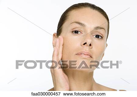 Stock Photo - Woman touching cheek, looking at camera. Fotosearch
