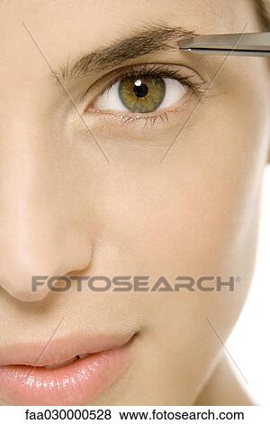 Woman tweezing eyebrow, looking at camera, cropped view View Large Photo Image Stock Photo - Woman tweezing eyebrow, looking at camera, cropped view. Fotosearch