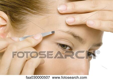 Woman tweezing her eyebrows, close-up View Large Photo Image Stock Photo - Woman tweezing her eyebrows, close-up. Fotosearch