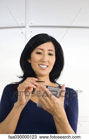 Woman using electronic organizer, smiling View Large Photo Image Stock Image - Woman using electronic organizer, smiling. Fotosearch