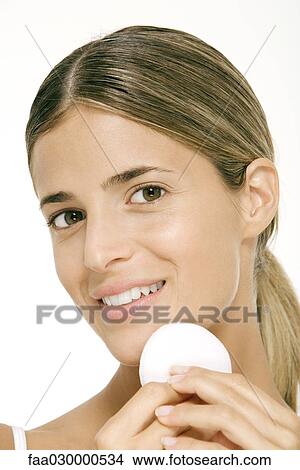 Woman using powder puff on cheek, smiling at camera View Large Photo Image Picture - Woman using powder puff on cheek, smiling at camera. Fotosearch