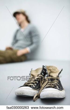 Worn canvas shoes, young man sitting in background View Large Photo Image Stock Image - Worn canvas shoes, young man sitting in background. Fotosearch