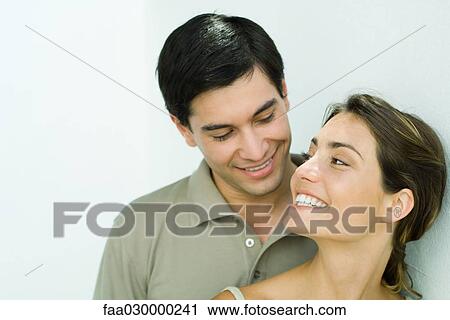 Stock Image - Young couple smiling at each other. Fotosearch