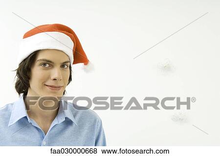 Young male wearing Santa hat, smiling at camera, portrait View Large Photo Image Stock Photo - Young male wearing Santa hat, smiling at camera, portrait. Fotosearch