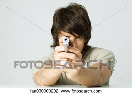 Young man aiming gun at camera View Large Photo Image Stock Image - Young man aiming gun at camera. Fotosearch