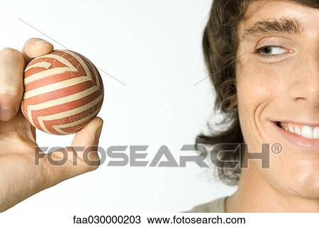 Young man holding ball, smiling, cropped view View Large Photo Image Stock Image - Young man holding ball, smiling, cropped view. Fotosearch