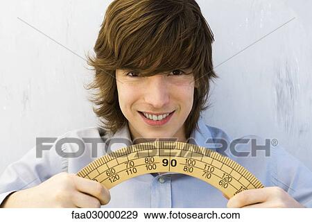 Young man holding potractor in both hands, smiling at camera View Large Photo Image Stock Photo - Young man holding potractor in both hands, smiling at camera. Fotosearch