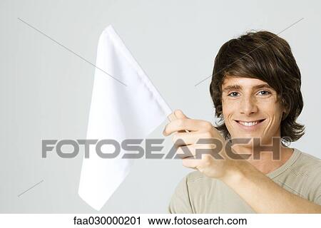 Young man holding white flag, smiling at camera View Large Photo Image Stock Image - Young man holding white flag, smiling at camera. Fotosearch