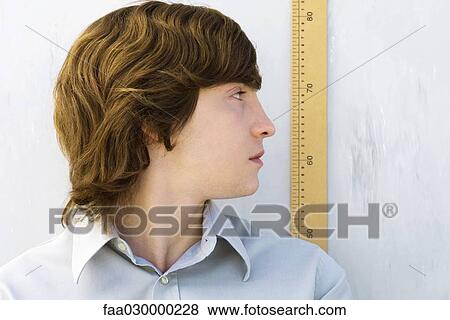 Young man looking over shoulder at yardstick, close-up View Large Photo Image Stock Photo - Young man looking over shoulder at yardstick, close-up. Fotosearch