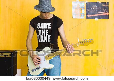 Young man playing guitar, wearing "save the planet" tee-shirt View Large Photo Image Stock Photo - Young man playing guitar, wearing "save the planet" tee-shirt. Fotosearch