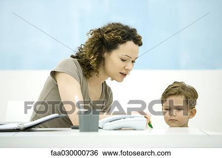 Young mother sitting at desk, interacting with little boy View Large Photo Image Stock Photograph - Young mother sitting at desk, interacting with little boy. Fotosearch