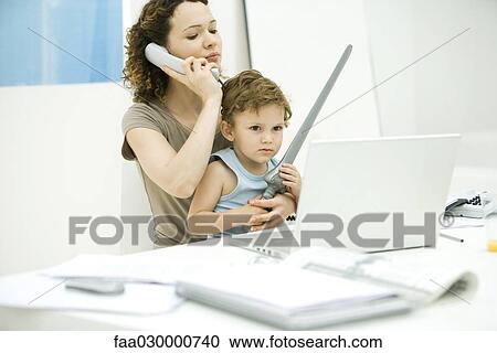 Young mother sitting at desk using phone while son sits on lap, holding sword View Large Photo Image Stock Image - Young mother sitting at desk using phone while son sits on lap, holding sword. Fotosearch