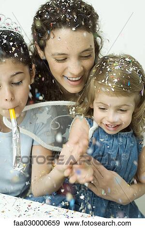 Stock Photo - Young woman and two little girls throwing confetti, all smiling. Fotosearch