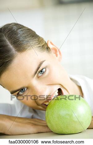 Stock Photograph - Young woman biting into apple. Fotosearch