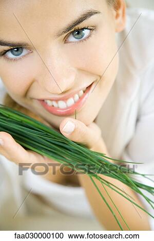 Young woman holding bunch of chives close to face View Large Photo Image Stock Image - Young woman holding bunch of chives close to face. Fotosearch