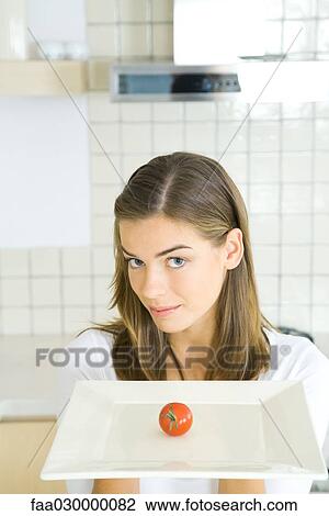 Young woman holding out tray with single tomato View Large Photo Image Stock Image - Young woman holding out tray with single tomato. Fotosearch