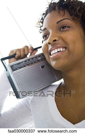 Young woman holding radio on shoulder, looking away, smiling View Large Photo Image Stock Photo - Young woman holding radio on shoulder, looking away, smiling. Fotosearch