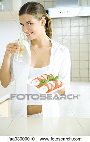 Young woman holding tomato and mozzarella salad, smelling salad dressing View Large Photo Image Stock Image - Young woman holding tomato and mozzarella salad, smelling salad dressing. Fotosearch