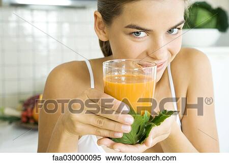 Young woman holding up glass of fresh vegetable juice View Large Photo Image Stock Photography - Young woman holding up glass of fresh vegetable juice. Fotosearch