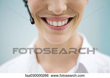 Young woman in headset, smiling at camera, cropped view View Large Photo Image Stock Photograph - Young woman in headset, smiling at camera, cropped view. Fotosearch