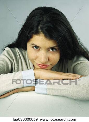 Young woman resting head on arms, smiling at camera, portrait View Large Photo Image Stock Photo - Young woman resting head on arms, smiling at camera, portrait. Fotosearch