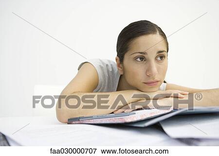 Young woman sitting with notebook, head resting on arms, looking away View Large Photo Image Stock Photo - Young woman sitting with notebook, head resting on arms, looking away. Fotosearch