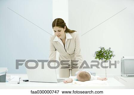 Young working mother using laptop, baby lying on desk View Large Photo Image Stock Photo - Young working mother using laptop, baby lying on desk. Fotosearch