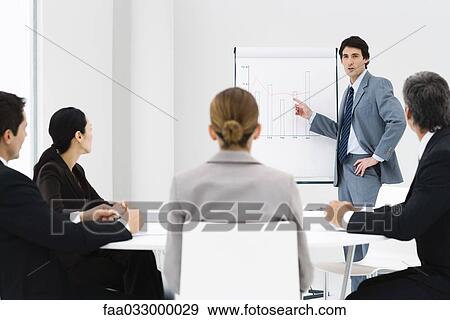 Stock Photo - Businessman making presentation, colleagues watching. Fotosearch