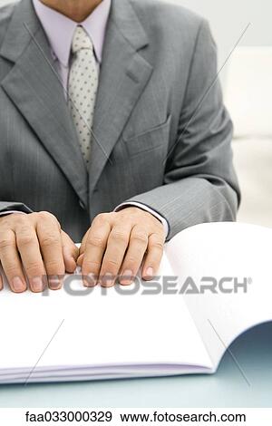 Stock Photo - Businessman reading braille document, cropped view. Fotosearch