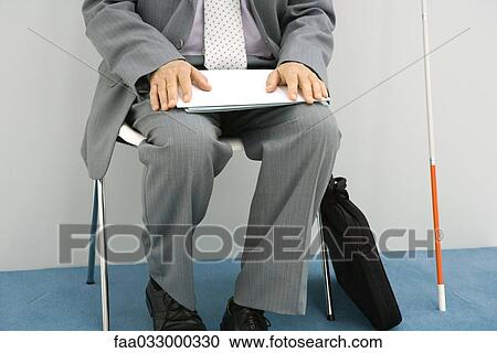 Businessman sitting in chair, white cane propped beside him, holding document, cropped View Large Photo Image Stock Image - Businessman sitting in chair, white cane propped beside him, holding document, cropped. Fotosearch