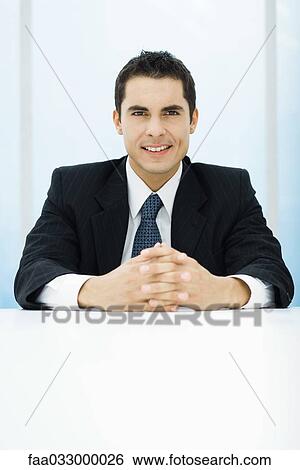 Businessman smiling at camera, hands clasped, portrait View Large Photo Image Stock Photograph - Businessman smiling at camera, hands clasped, portrait. Fotosearch