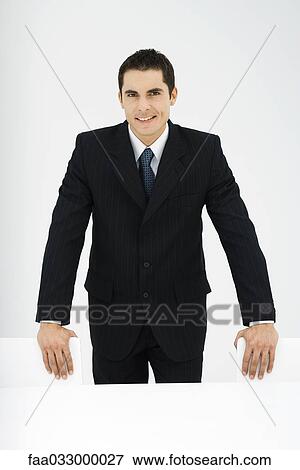 Businessman smiling at camera, standing, hands on chairs, portrait View Large Photo Image Stock Photo - Businessman smiling at camera, standing, hands on chairs, portrait. Fotosearch