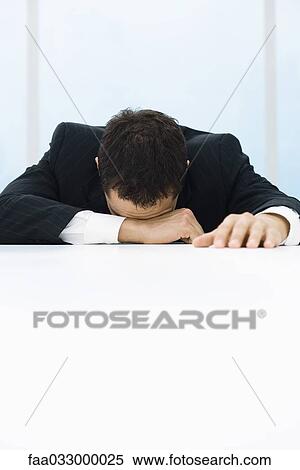 Stock Photography - Businessman with head down, arm over eyes. Fotosearch