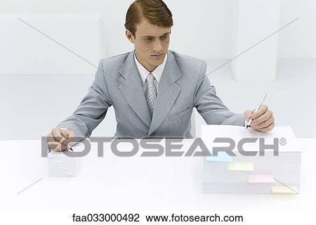 Businessman writing on two stacks of paper, one large, one small, pencil in each hand View Large Photo Image Stock Image - Businessman writing on two stacks of paper, one large, one small, pencil in each hand. Fotosearch