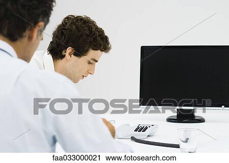Businessmen sitting near phone and monitor View Large Photo Image Stock Image - Businessmen sitting near phone and monitor. Fotosearch