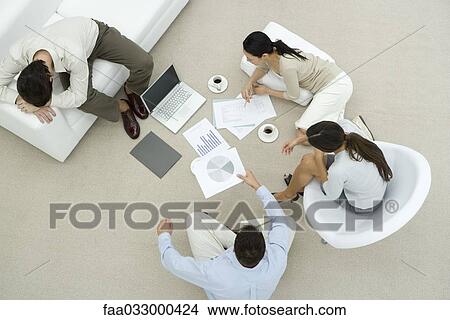 Picture - Colleagues discussing documents, two sitting on the floor, one resting head on arms, overhead view. Fotosearch