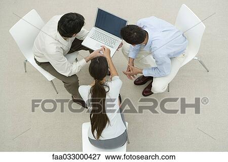 Stock Photo - Colleagues looking at laptop computer together, overhead view. Fotosearch