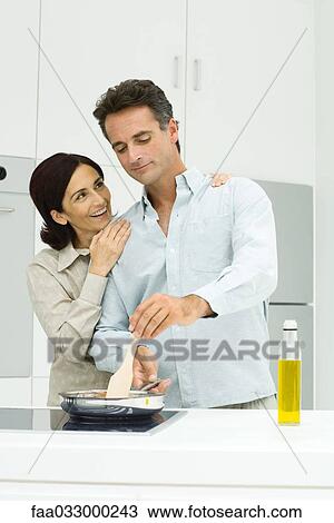 Couple cooking together in kitchen, woman putting hands on man's shoulders View Large Photo Image Stock Image - Couple cooking together in kitchen, woman putting hands on man's shoulders. Fotosearch