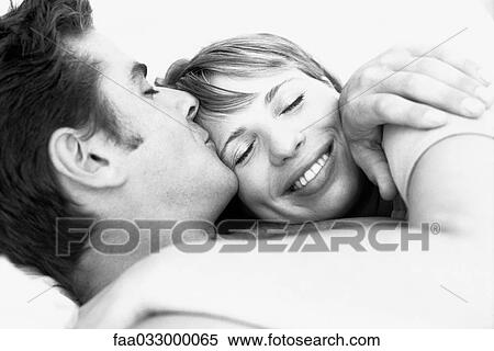 Stock Photography - Couple embracing, man kissing woman's forehead, woman's eyes closed. Fotosearch