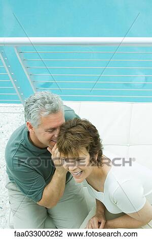 Couple sitting on balcony, man whispering in woman's ear, high angle view View Large Photo Image Stock Image - Couple sitting on balcony, man whispering in woman's ear, high angle view. Fotosearch