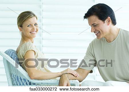 Couple sitting on porch, woman touching man's arm and smiling at camera, man looking down View Large Photo Image Stock Image - Couple sitting on porch, woman touching man's arm and smiling at camera, man looking down. Fotosearch