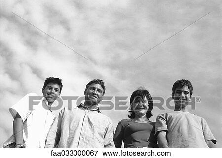 Family standing outdoors, group portrait, low angle view View Large Photo Image Stock Photo - Family standing outdoors, group portrait, low angle view. Fotosearch