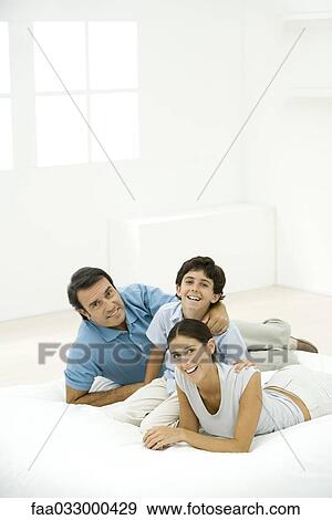 Stock Photo - Family together on mattress, all smiling at camera. Fotosearch