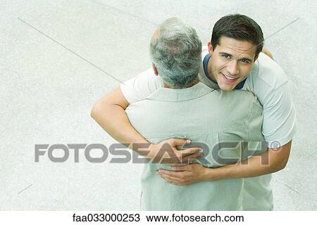 Father and adult son embracing, son smiling at camera, high angle view View Large Photo Image Stock Image - Father and adult son embracing, son smiling at camera, high angle view. Fotosearch