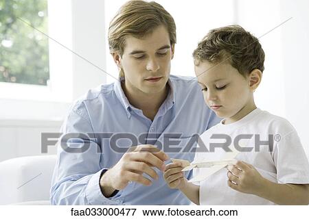 Stock Photo - Father and son looking at toy airplane together. Fotosearch