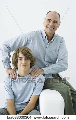 Father and son sitting on sofa, man's hands on teen boy's shoulders, portrait View Large Photo Image Picture - Father and son sitting on sofa, man's hands on teen boy's shoulders, portrait. Fotosearch