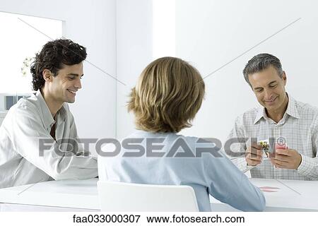 Stock Photo - Father and two sons playing cards together. Fotosearch